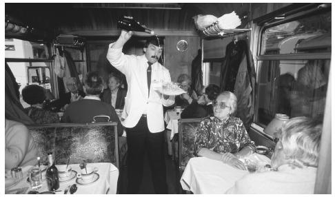 A waiter pours drinks on the Glacier Express, a famous mountain railway that makes a nearly eight-hour journey between Saint Moritz and Zermatt.